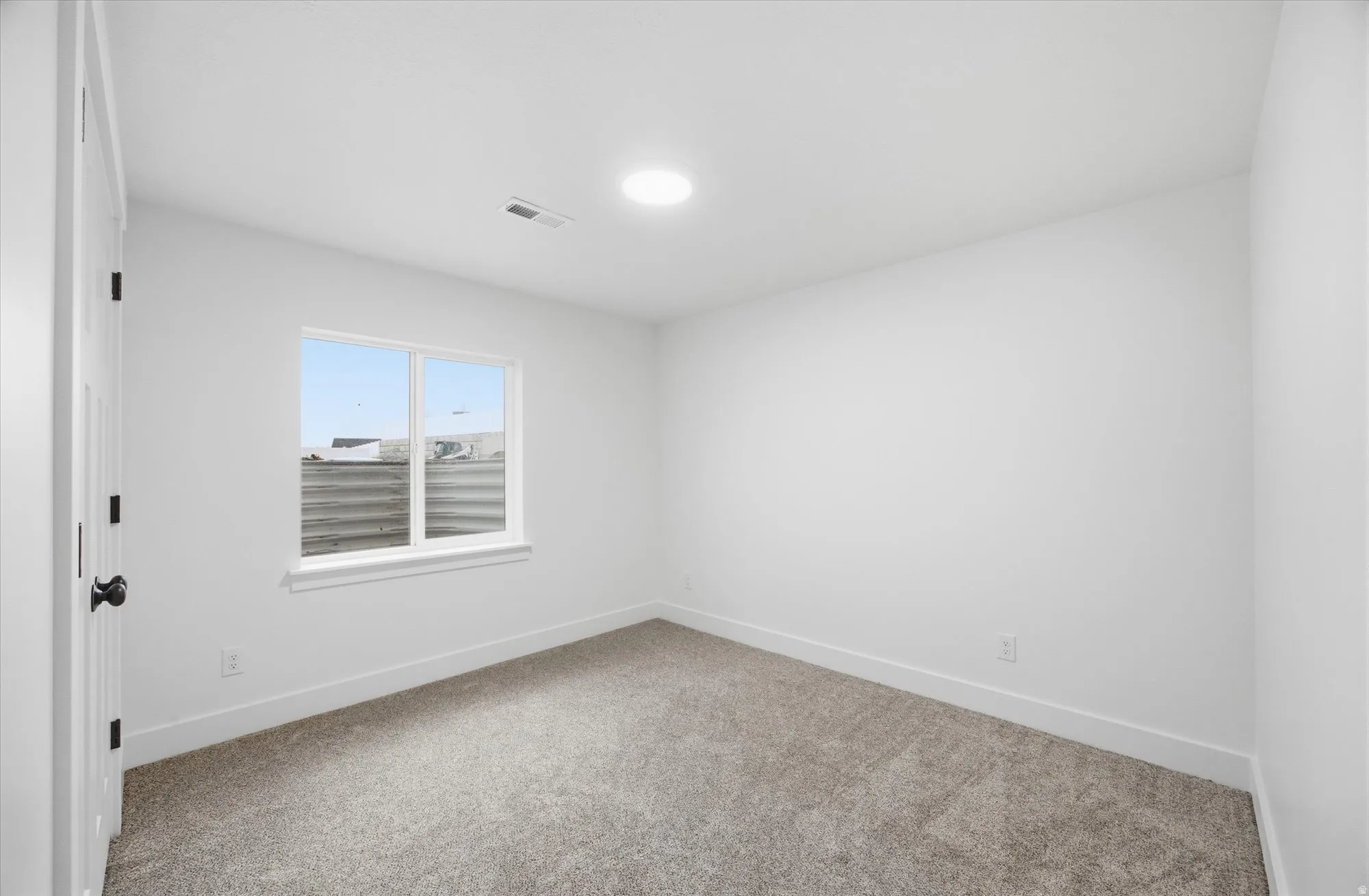 Empty room with baseboards and light colored carpet