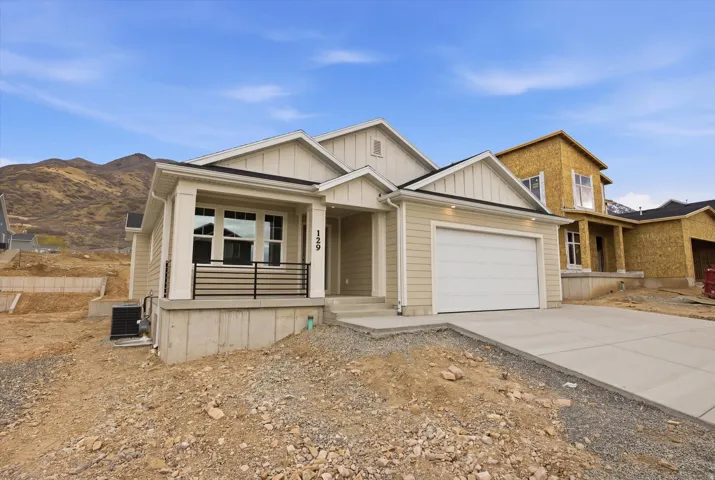 View of front of house featuring covered porch, driveway, an attached garage, and board and batten siding