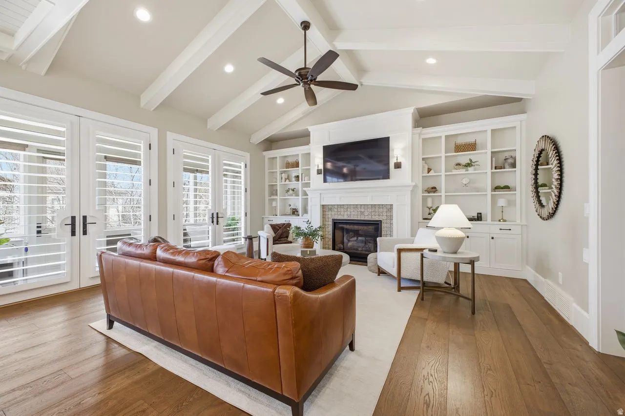 Living room with hardwood / wood-style floors, recessed lighting, french doors, a glass covered fireplace, and a ceiling fan