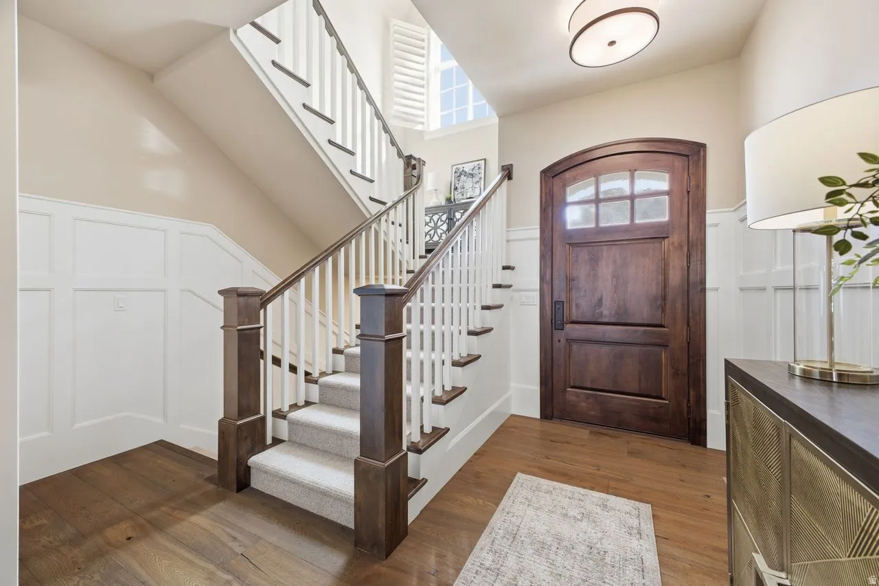 Entrance foyer featuring dark wood-style floors, a decorative wall, wainscoting, and vaulted ceiling