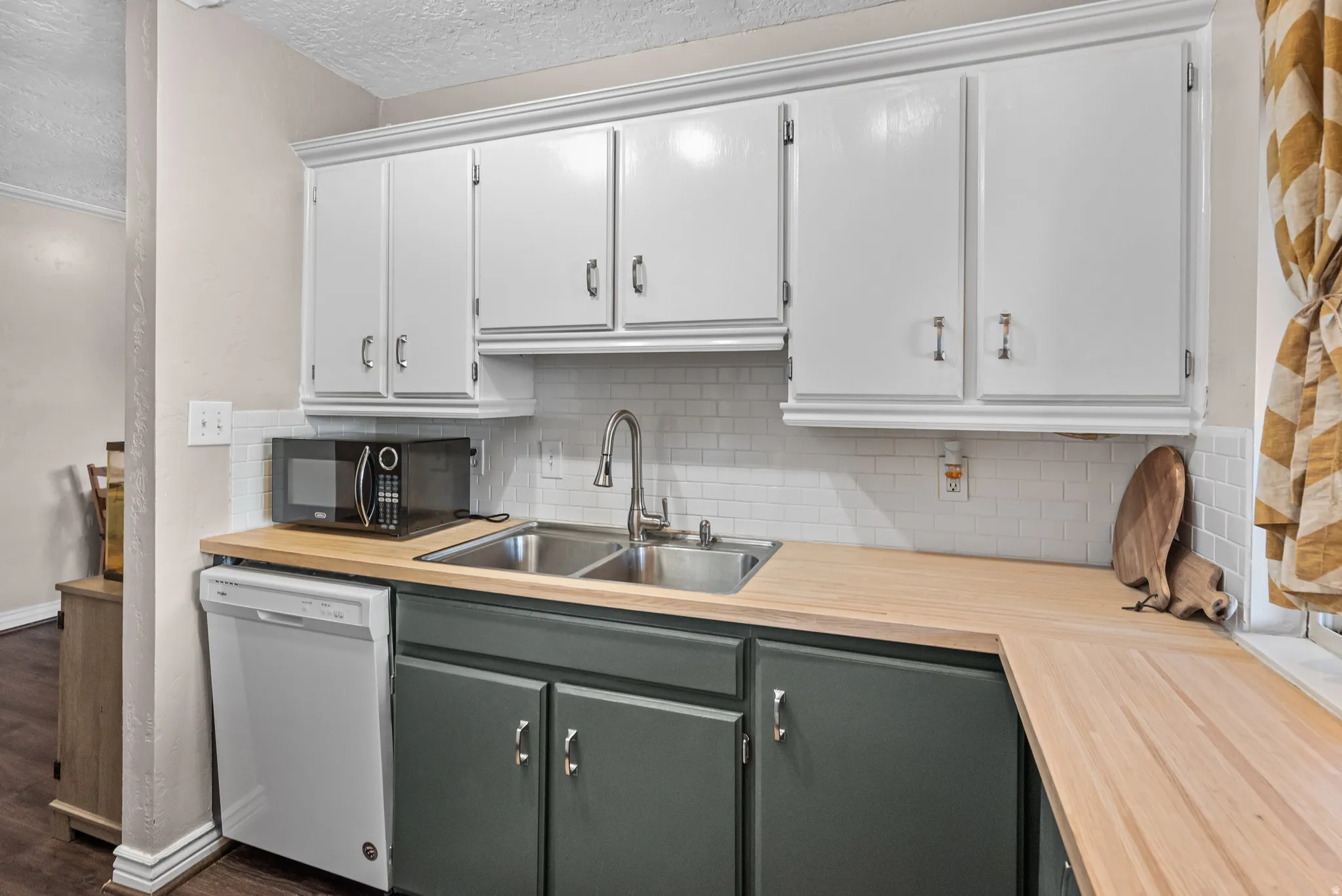 Kitchen featuring dishwasher, a textured ceiling, backsplash, wooden counters, and black microwave