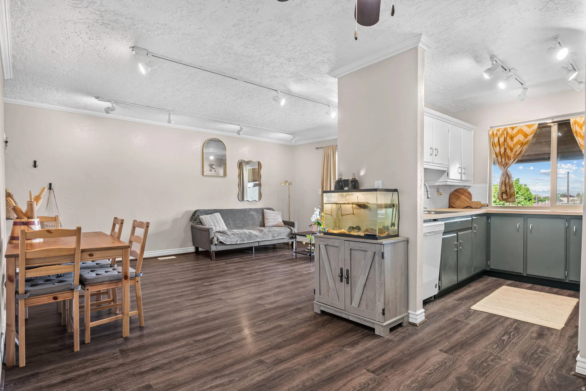 Dual tone kitchen featuring rail lighting, a textured ceiling, dark wood-style floors, ceiling fan, and light countertops