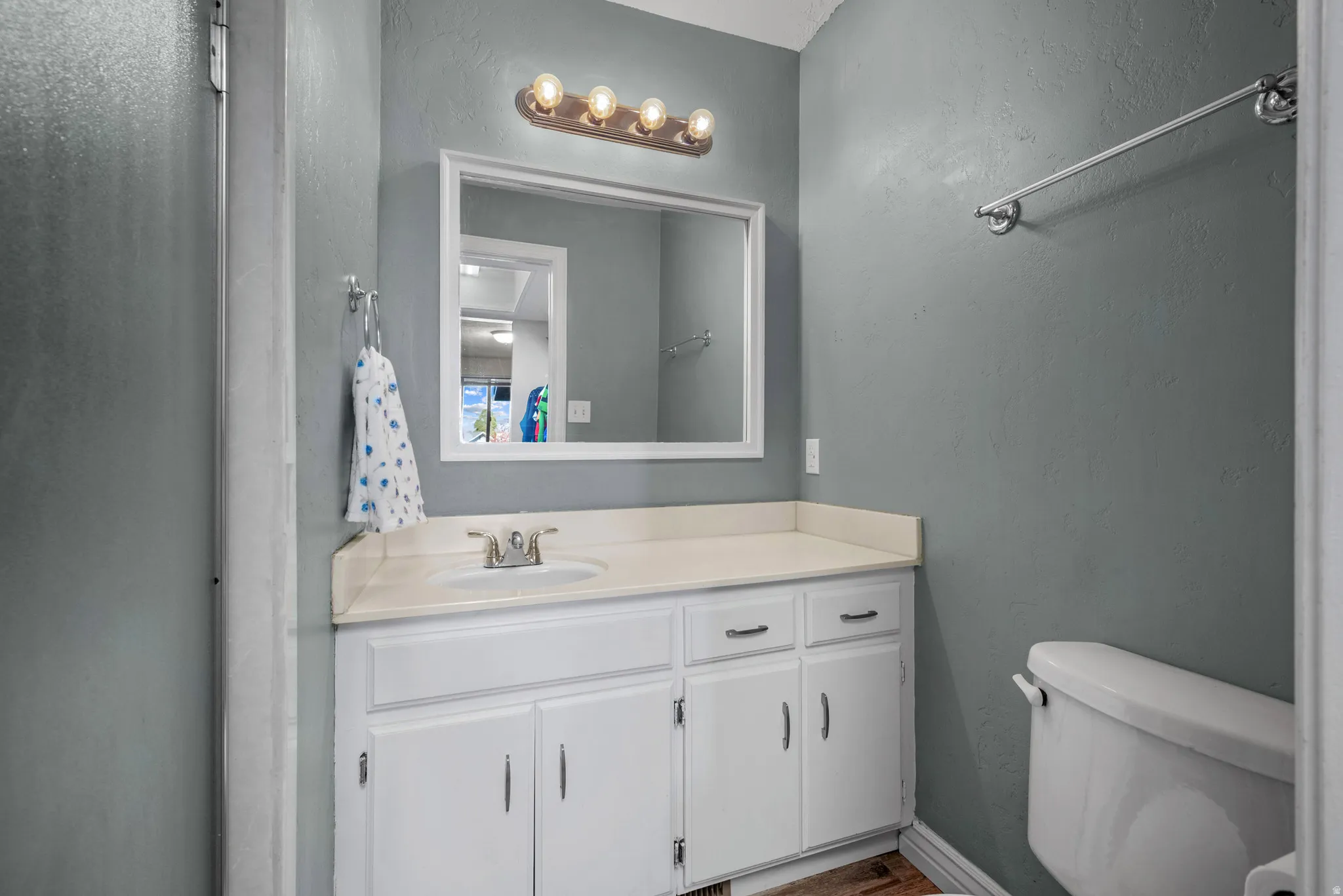 Half bathroom featuring vanity and a textured wall