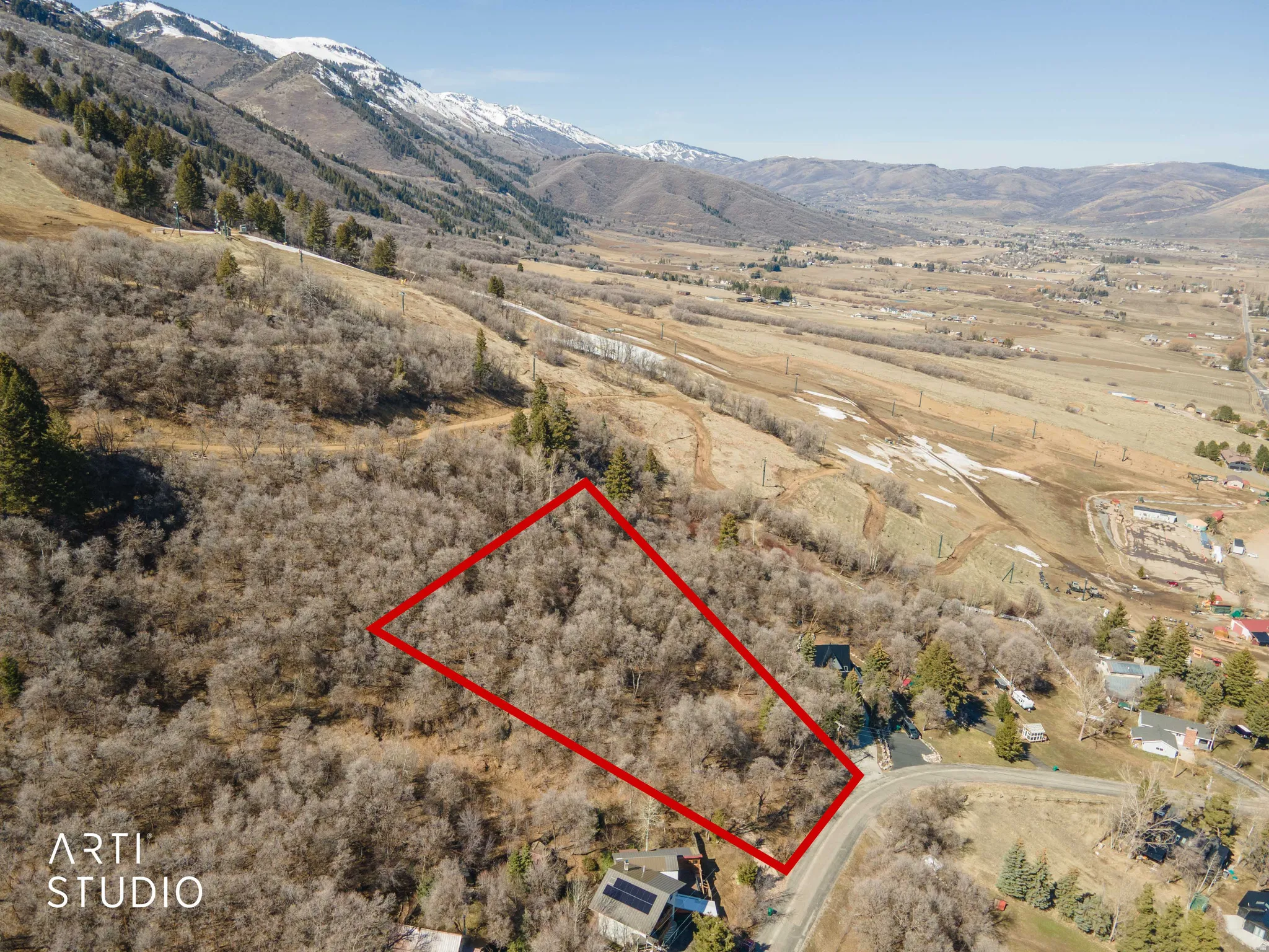 Aerial view of sparsely populated area with property boundaries highlighted and a mountainous background