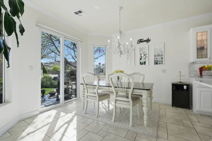 Dining area featuring hanging lights, crown molding, wine cooler, and light tile patterned floors