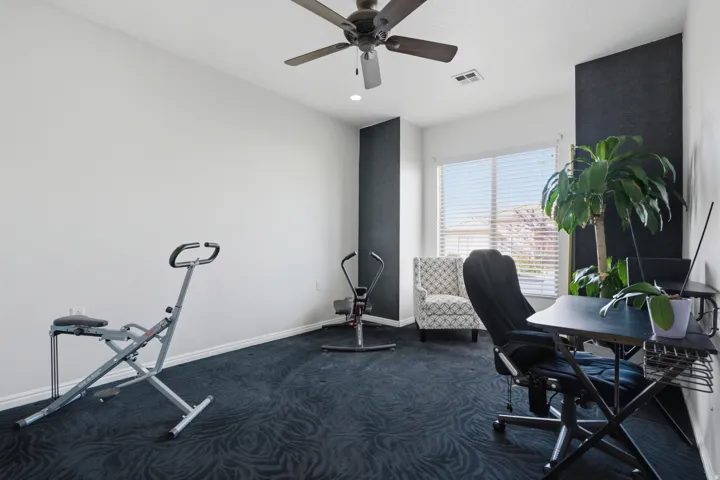 Home office featuring dark colored carpet, ceiling fan, and recessed lighting