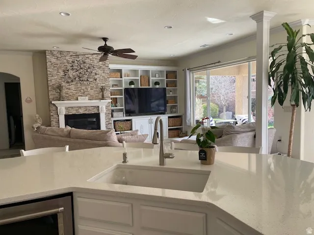 Kitchen with white cabinets, open floor plan, a fireplace, light stone counters, and beverage cooler