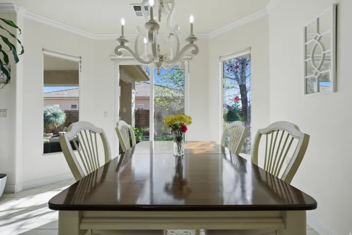 Dining area with suspended lighting, ornamental molding, plenty of natural light, and light tile patterned floors
