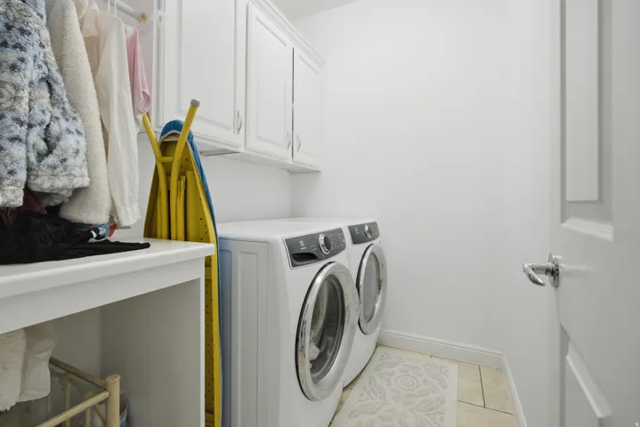 Laundry area featuring cabinet space, washer and clothes dryer, and light tile patterned flooring