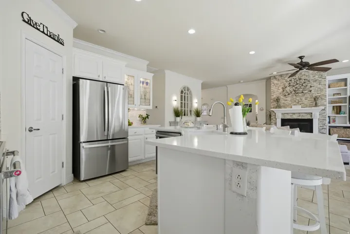Kitchen featuring white cabinetry, stainless steel appliances, a breakfast bar area, ornamental molding, and light stone countertops