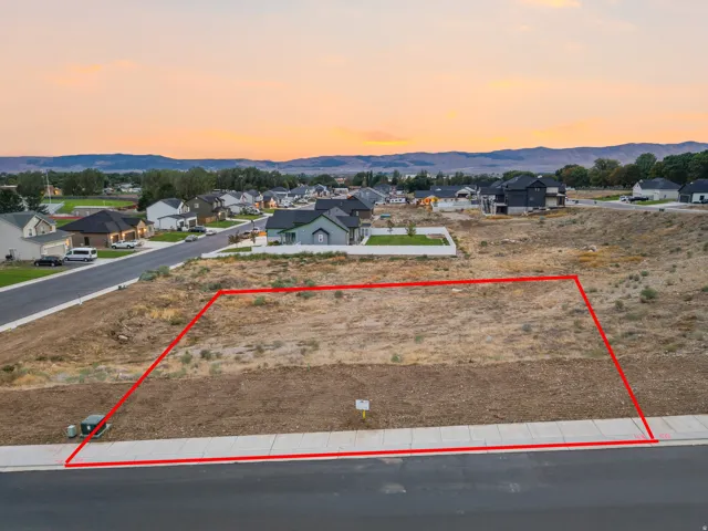Level building lot featuring a paved street and concrete sidewalk