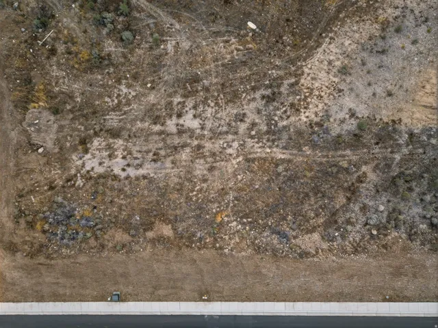 Undeveloped lot with visible road frontage, sidewalk, and utility access points