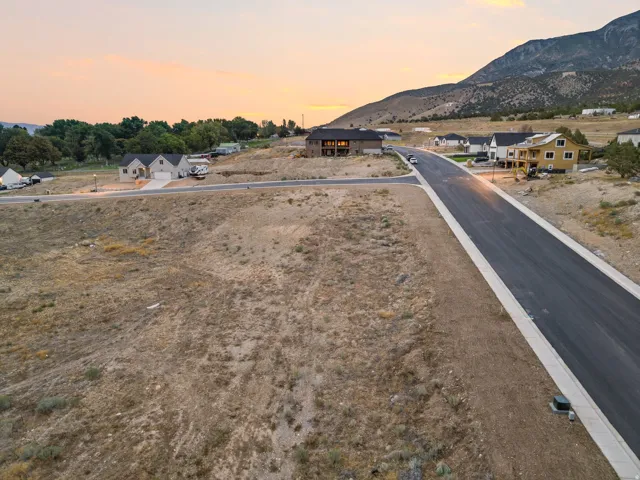 Expansive undeveloped lot with street frontage, featuring a mountainous backdrop and proximity to developed residential properties