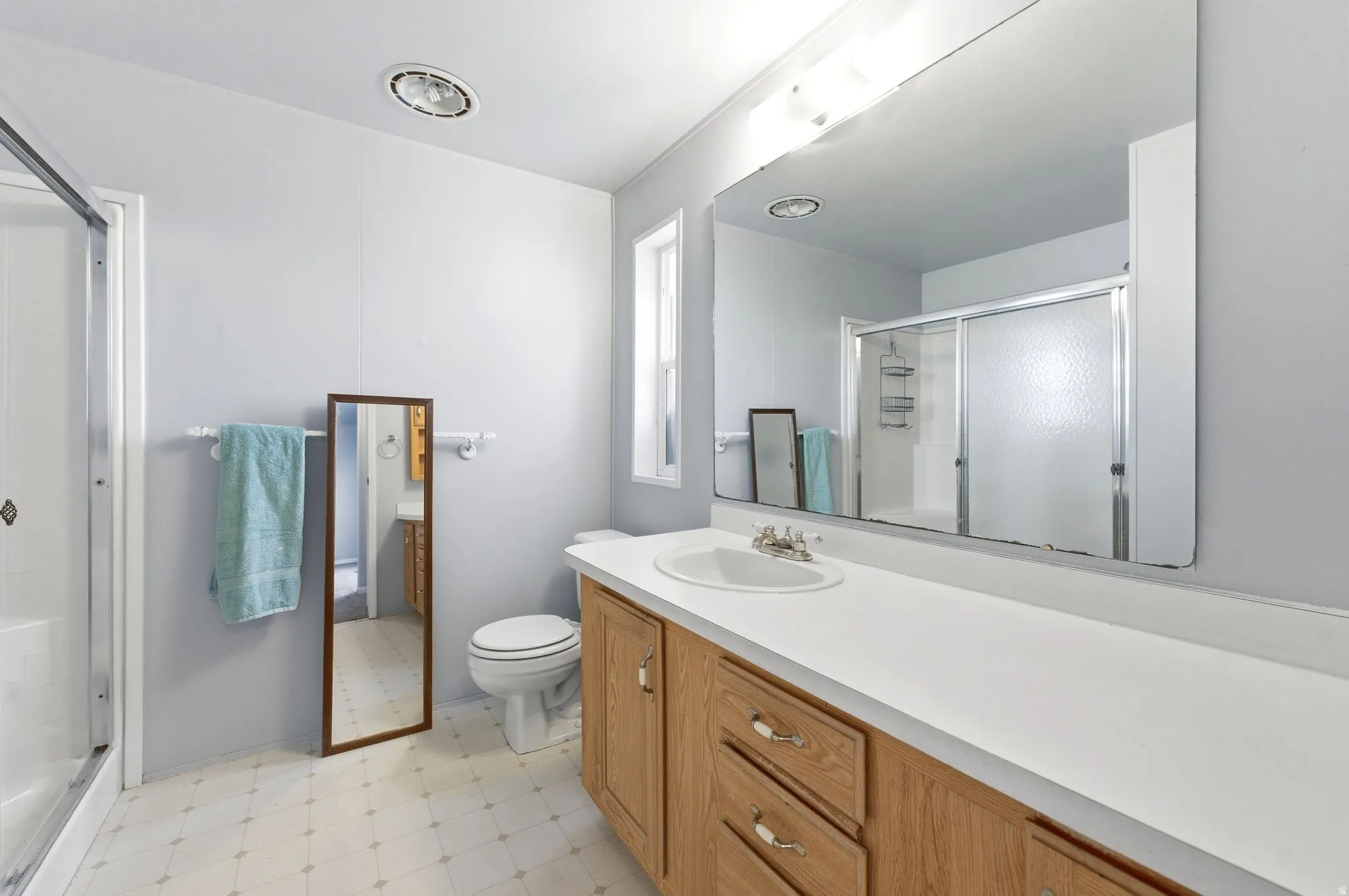 Full bathroom featuring light floors, vanity, and a stall shower