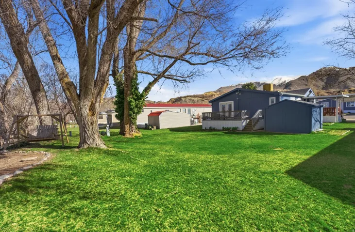 View of grassy yard with a deck with mountain view and stairs