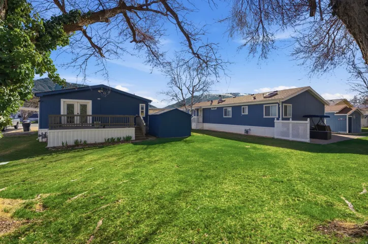 Rear view of property featuring a wooden deck, a storage shed, and a lawn
