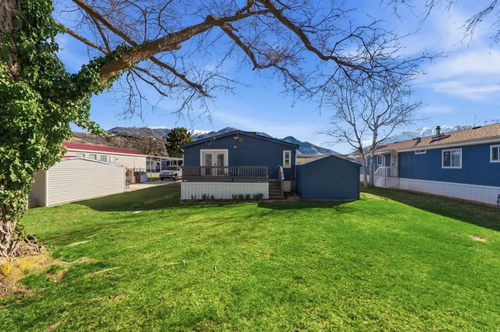 Rear view of property featuring a lawn, a deck with mountain view, a storage shed, and french doors