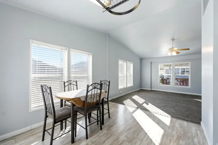 Dining space featuring healthy amount of natural light, light wood-style floors, a ceiling fan, and vaulted ceiling