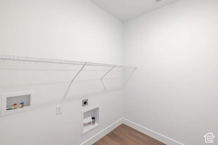 Laundry area with wood-finish flooring, white walls, and a wire shelf