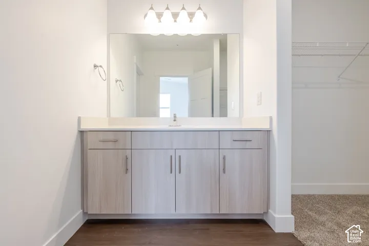 Vanity with a light wood-finish cabinet, integrated sink, and white countertop