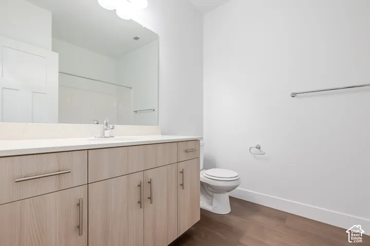 Bathroom featuring a vanity with wood-finish cabinetry, a large integrated mirror, and a white countertop