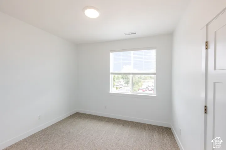Recessed ceiling light, neutral wall paint, window with blinds, light-colored carpeting, and a white panel door
