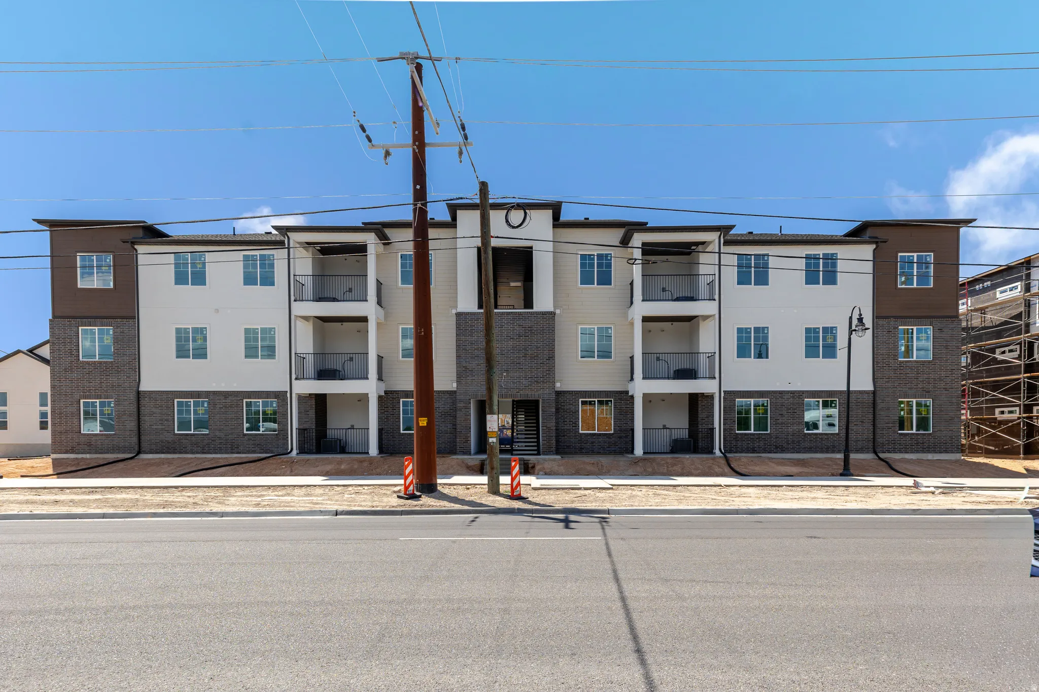 Contemporary multi-story building featuring brick and siding facade, private balconies with black railings, and multiple windows