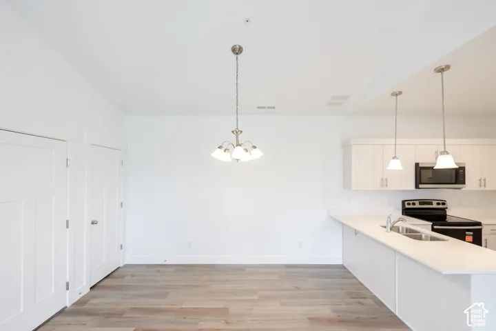 Wood-finish flooring, white walls, built-in kitchen cabinetry, stainless steel microwave, and integrated sink