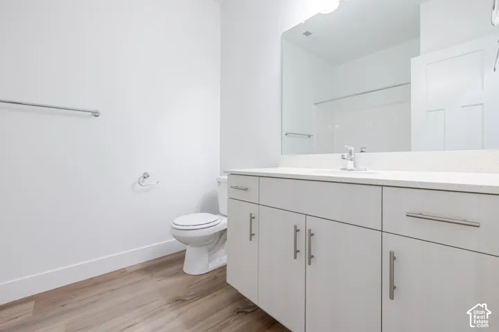 Modern bathroom featuring wood-finish flooring, a white vanity with brushed nickel hardware, and a white countertop
