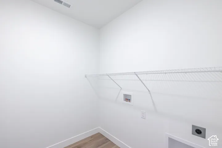 Laundry area featuring wood-finish flooring and a wire shelving system