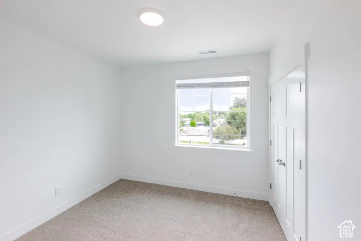 Recessed ceiling lighting, white interior walls, window with blinds, paneled interior door, and carpet flooring