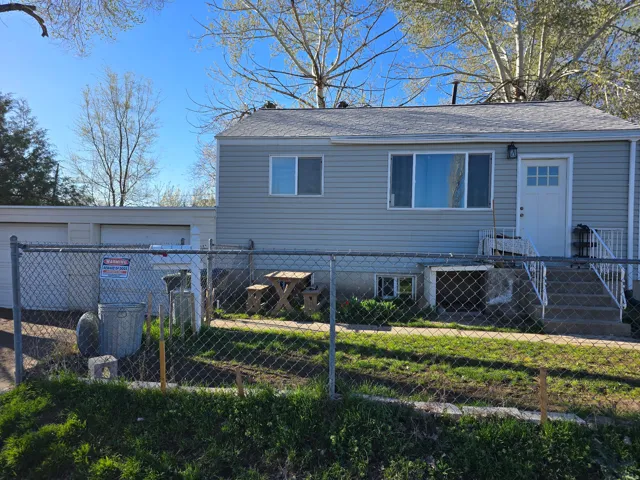 View of front of property with a fenced front yard, roof with shingles, and a garage
