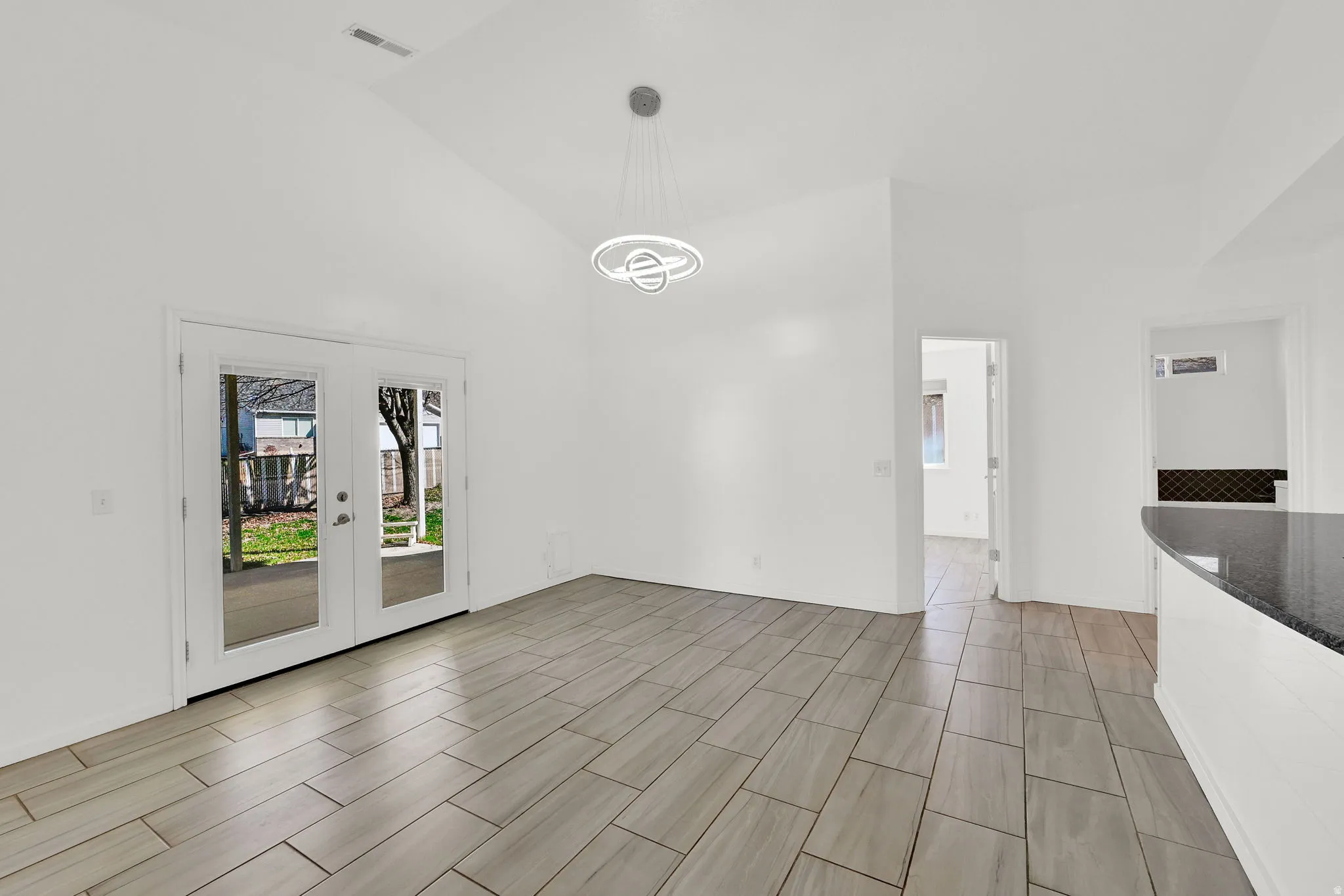 Unfurnished dining area featuring lofted ceiling and french doors, doggie door