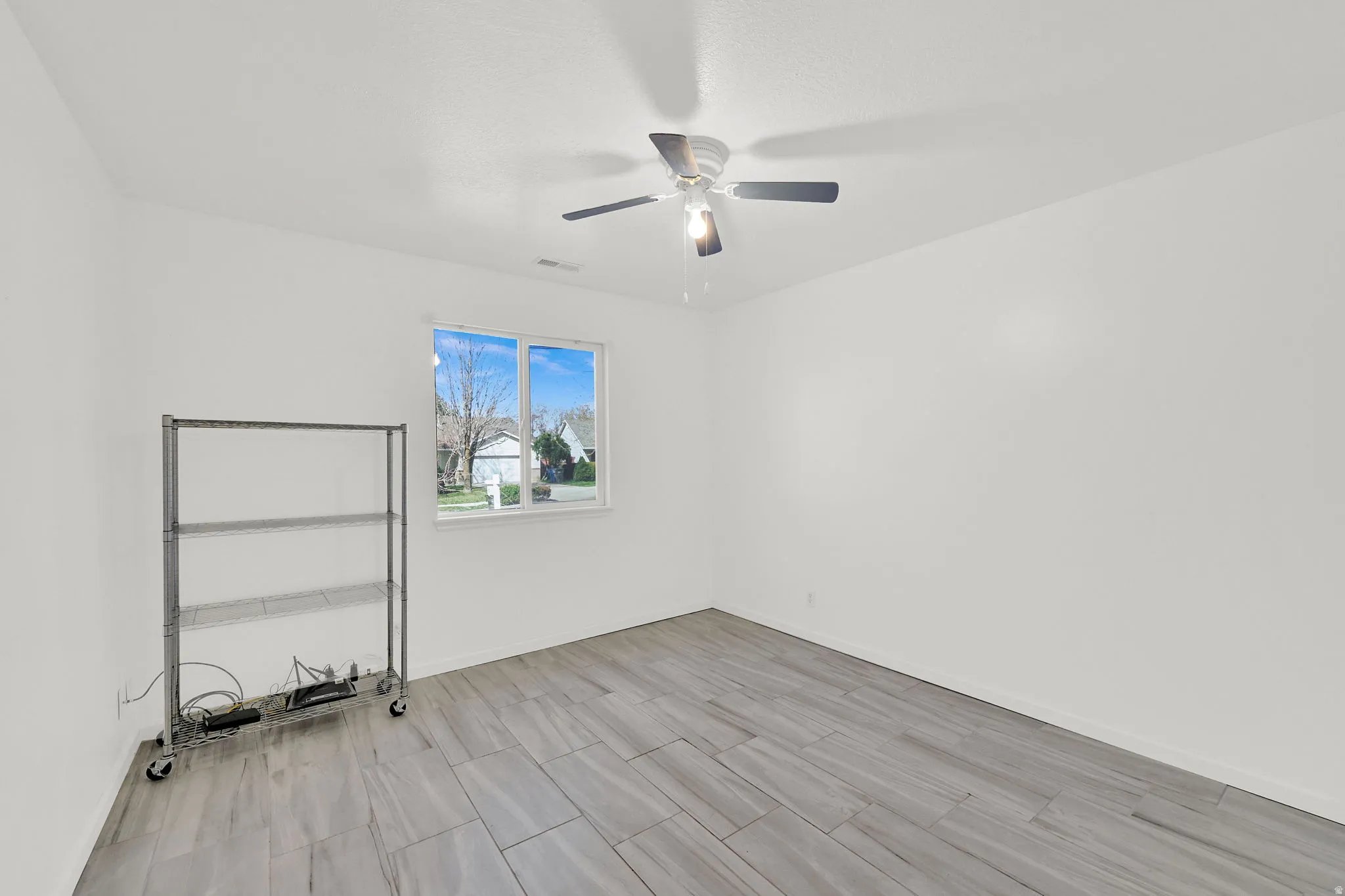 Empty room with ceiling fan and tile floors