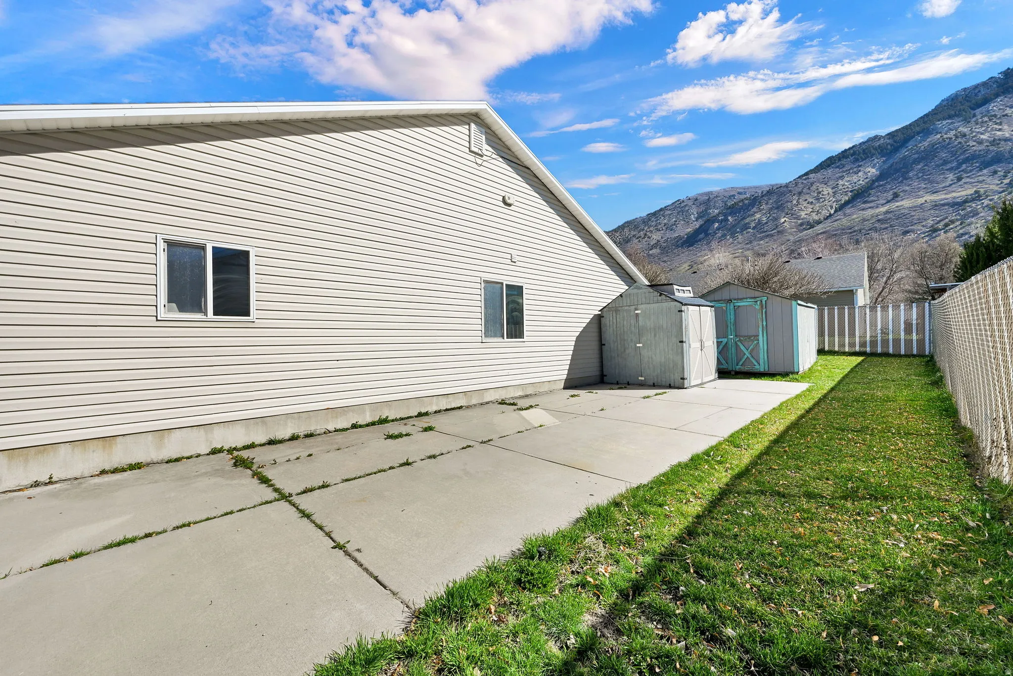 Rear view of house featuring 2 storage sheds, a fenced backyard for security, a covered patio, and a mountain view