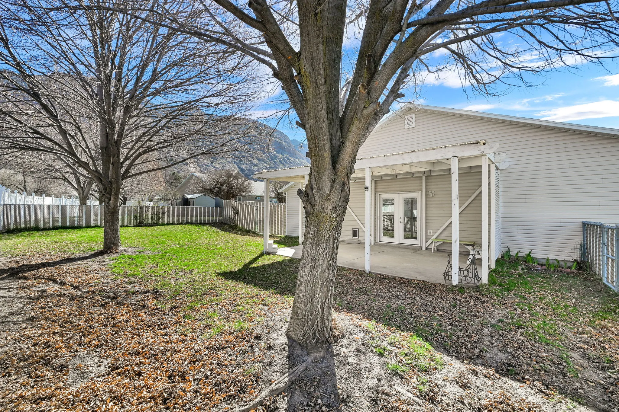 Fenced backyard featuring french doors and covered patio area