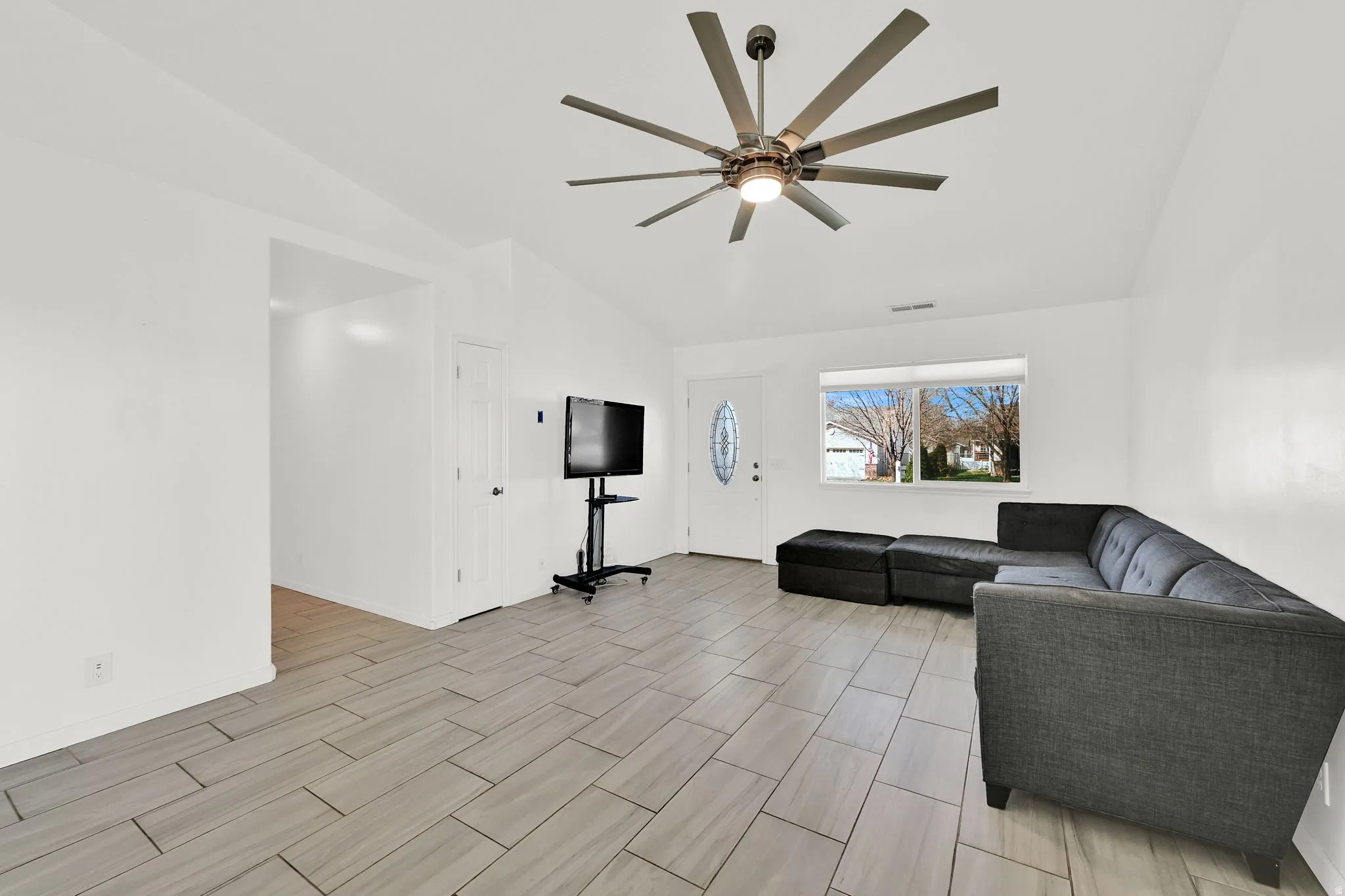 Living room featuring lofted ceiling, a ceiling fan, and title floors