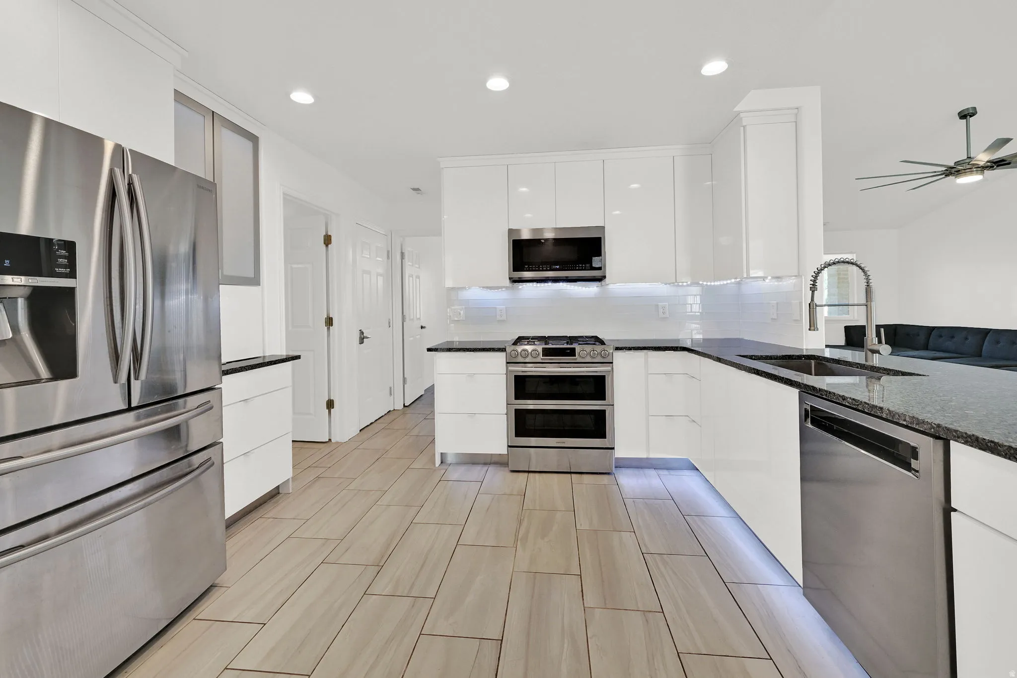 UPDATED Kitchen with white cabinetry, stainless steel appliances, modern cabinets, tasteful backsplash, and recessed lighting