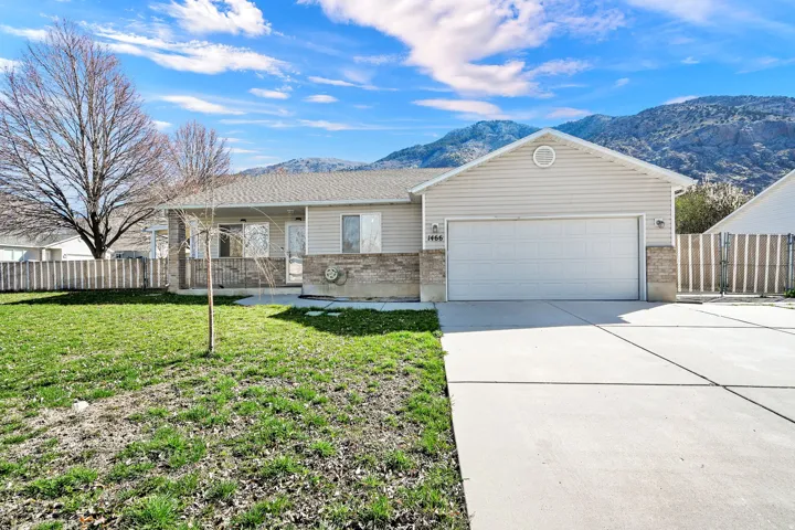 Single story home with brick siding, an attached garage, concrete driveway, and a mountain view