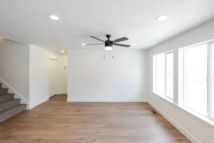 Spacious room featuring wood-finish flooring, recessed lighting, and a ceiling fan