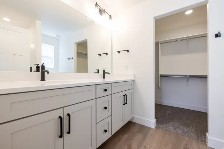 Dual vanity with light gray shaker-style cabinetry, white countertops, and matte black fixtures