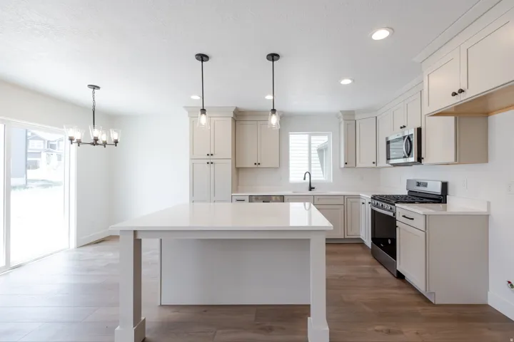 Contemporary kitchen featuring white cabinetry, a central island with a solid surface countertop, wood-finish flooring, recessed lighting, and stainless steel appliances