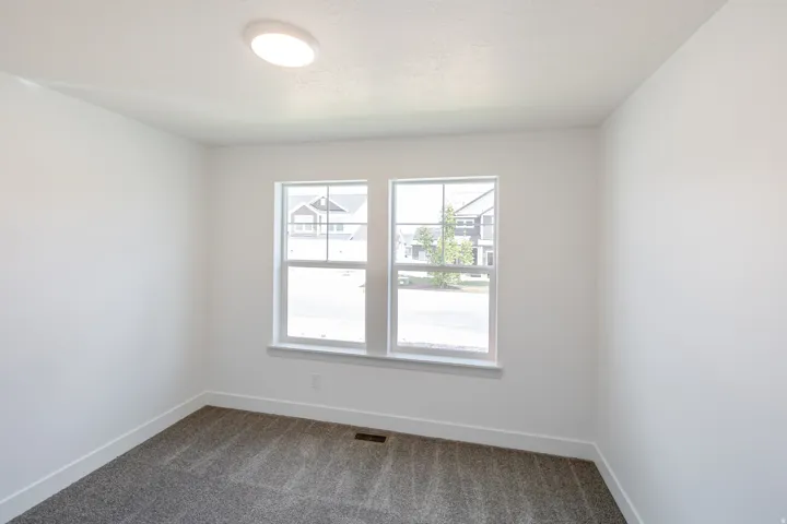 Neutral-toned room featuring a flush-mount ceiling light fixture, two double-hung windows with white trim, white baseboards, and carpet flooring