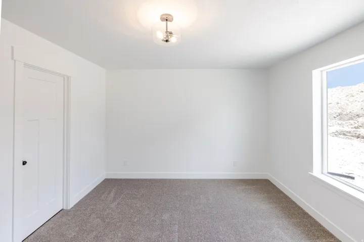 Neutral tone carpet flooring with white baseboards and walls