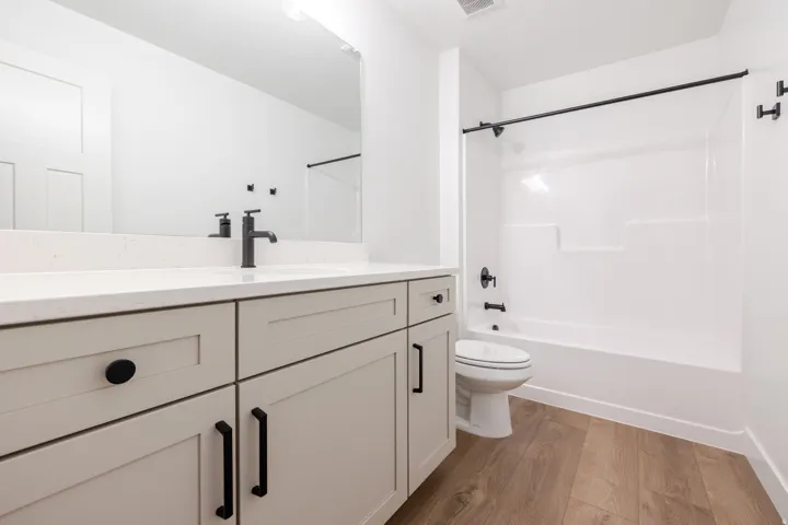Bathroom featuring a light-toned vanity with black hardware, a white countertop, and a wide mirror