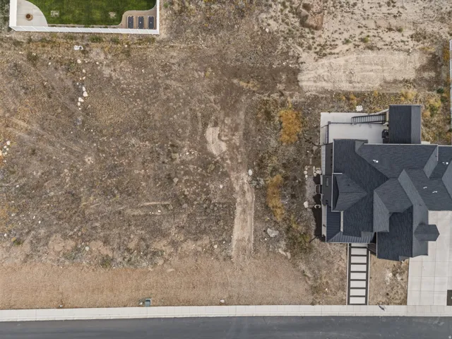 Newly constructed residence with a multi-gabled roofline, concrete driveway, and an adjacent undeveloped lot