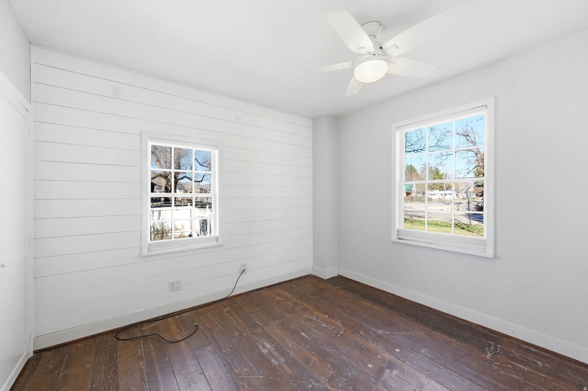 Empty room with dark wood-style floors and ceiling fan