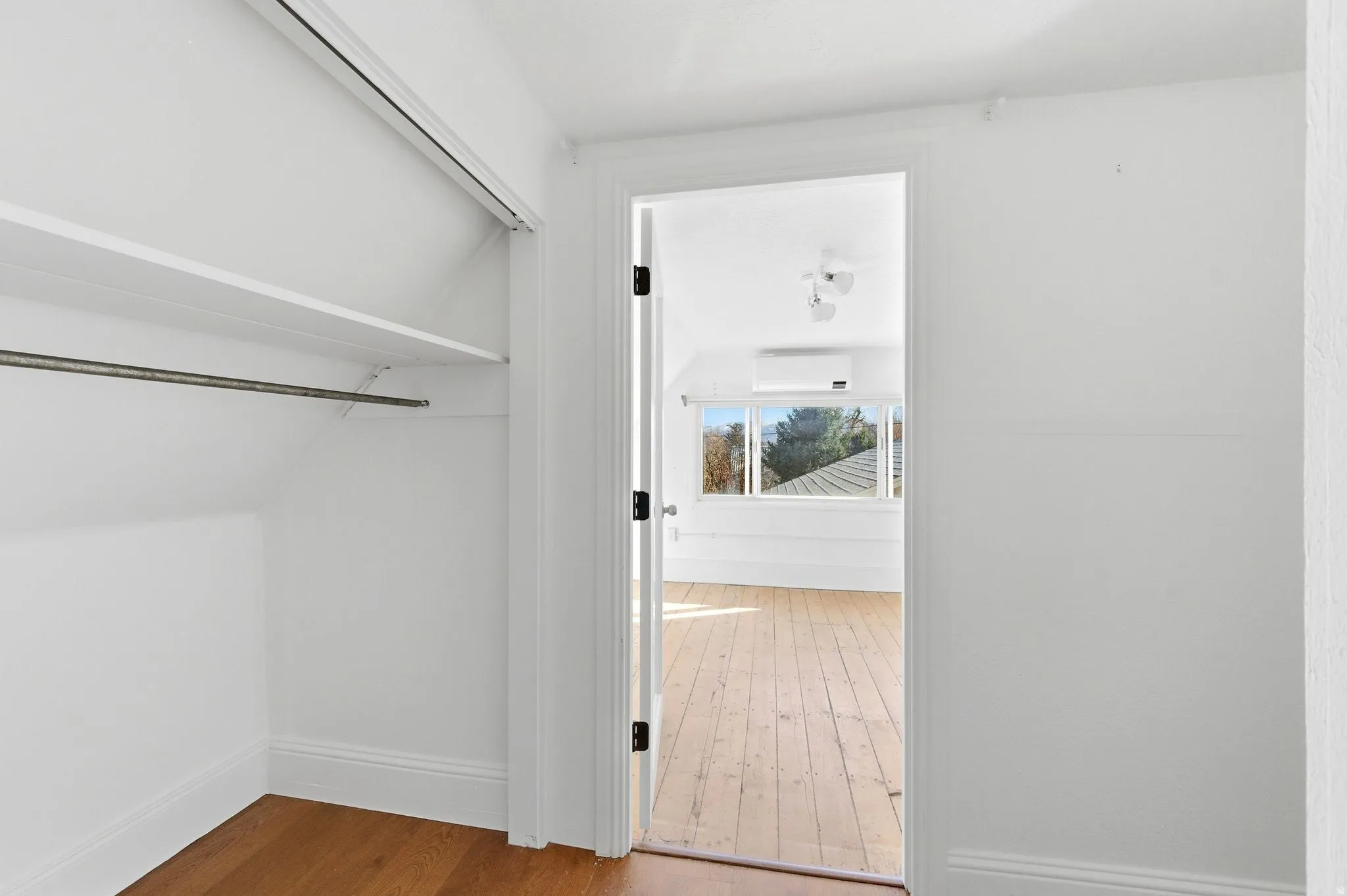 Walk in closet featuring light wood-type flooring and a wall unit AC