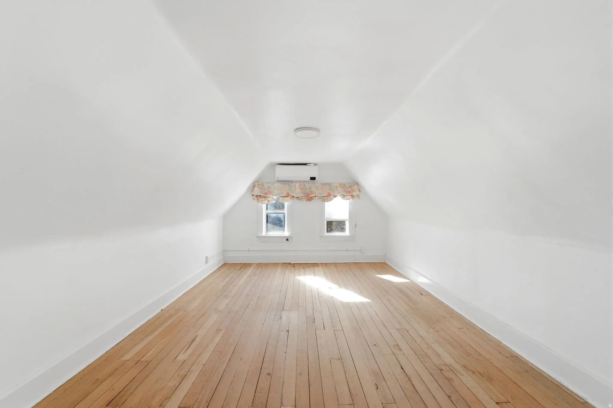 Bonus room featuring baseboards and light wood-type flooring