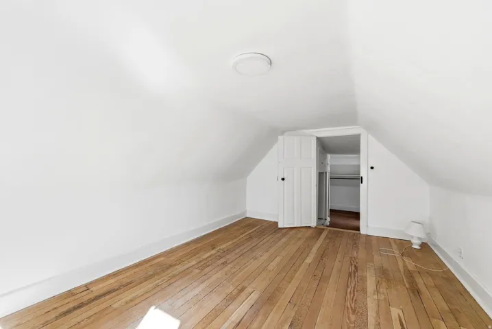 Additional living space featuring light wood-style floors and vaulted ceiling